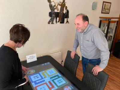 Leiterin Iris Krause zeigt Thomas Staudt den beliebten Spieletisch.